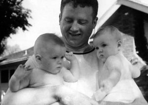 Manon's father carrying her and her twin, Shirley